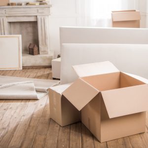 Close-up view of cardboard boxes and furniture in empty room, relocation concept Ordnung in besonderen Lebenssituationen – Unterstützung bei Umzug